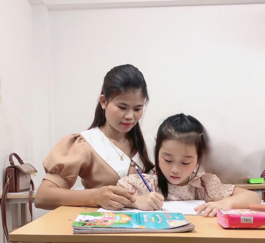 Hình ảnh cô giáo Thắm đang hướng dẫn học sinh luyện viết